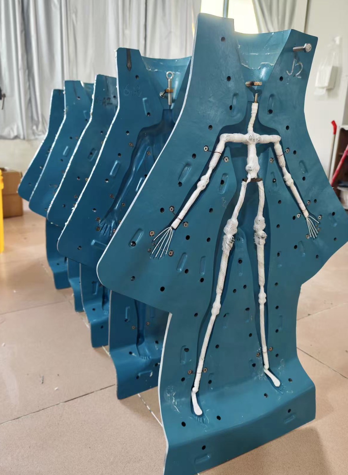 Row of upright body molds in the LORIBEAR workshop, the front mold open with the wrapped metal skeleton positioned inside before casting